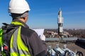 Professional industrial climber in helmet and uniform reads technical documentation and antennas of GSM DCS UMTS LTE Royalty Free Stock Photo