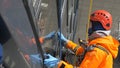 Industrial climber in orange suit washes windows during latex glove pandemic of coronovirus