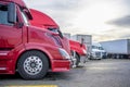 Professional industrial grade carriers big rig semi trucks with semi trailers standing on the truck stop parking for the truck Royalty Free Stock Photo