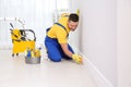 Janitor cleaning baseboard with brush after renovation