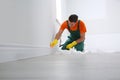 Professional janitor cleaning baseboard with brush after renovation