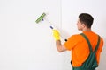 Professional janitor cleaning white brick wall with squeegee indoors. Space for text