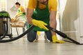 Professional janitor in uniform vacuuming floor indoors, closeup Royalty Free Stock Photo