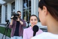 Professional journalist and operator with video camera taking interview outdoors Royalty Free Stock Photo
