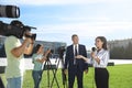 Professional journalist and operators with video cameras taking interview outdoors Royalty Free Stock Photo