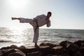 Image of male karate fighter posing on stones sea background