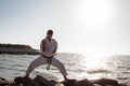 Image of male karate fighter posing on stones sea background Royalty Free Stock Photo
