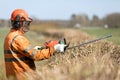 Professional Landscaper in uniform and hearing Protection Headphones trimming hedgerow with Gas Powered Clipper