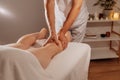 Professional legs massage in SPA salon on the background of candles. Handsome masseur therapist in white uniform making