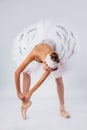 Professional legs of a young ballerina who puts on pointe shoes isolated on a white background in the studio. Ballet practice.
