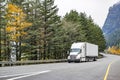 Professional long hauler big rig white semi truck transporting cargo in refrigerator semi trailer driving on wide autumn road Royalty Free Stock Photo