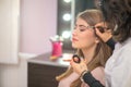 Professional make-up artist preparing model for studio shot. Royalty Free Stock Photo