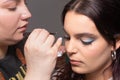 Professional makeup artist placing false eyelashes to a young woman Royalty Free Stock Photo