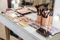 Professional makeup artist work space table with brushes, cosmetic products , eyeshadow palettes, Cosmetics of different