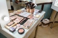 Professional makeup artist work space table with eyeshadow palettes, cosmetic products and brushes. Cosmetics of