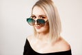 Professional makeup. Blond woman with bare shoulders and sunglasses posing on light studio background. Space for text Royalty Free Stock Photo