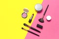 Professional makeup brushes, powder, eyeshadow, blush, lipstick on yellow pink background flat lay top view copy space. Beauty
