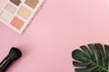 Professional makeup tools palette of multicolor cosmetic make up with a monstera leaf and a powder brush on pink background. Royalty Free Stock Photo