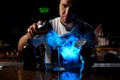 Professional male bartender pouring a brown alcoholic drink from the steel shaker to the glass under blue light Royalty Free Stock Photo