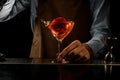 Professional male bartender throwing a big red rose bud to a martini glass with a brown cocktail Royalty Free Stock Photo