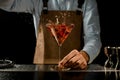 Professional male bartender throwing a red rose bud to a martini glass with a golden cocktail Royalty Free Stock Photo