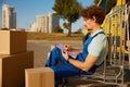 Professional male courier checking document for delivery while sitting outdoors