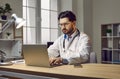 Professional male doctor filling documents using laptop computer Royalty Free Stock Photo