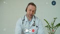 Professional male doctor in white medical coat and headset making conference call on laptop computer, consulting Royalty Free Stock Photo