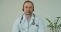 Professional male doctor in white medical coat and headset making conference call on laptop computer, consulting Royalty Free Stock Photo