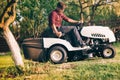 Professional male gardner using lawn mower for cutting grass in home garden Royalty Free Stock Photo