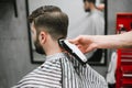 Professional male hairdresser does hairstyle to bearded man in barber shop, back view, barber`s hand with clipper. Barber clippin Royalty Free Stock Photo