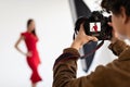 Professional male photographer and beautiful female model in red dress making beauty or content photoshoot in studio