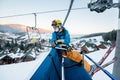 Skier guy sitting at ski chair lift in beautiful day and turns back. Close-up. Concept of skiing. Royalty Free Stock Photo