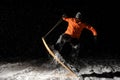 Professional male snowboarder jumping on snow at night