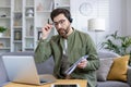 Man working from home using laptop and headset while taking notes during online meeting Royalty Free Stock Photo
