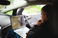 Professional man with a laptop in car tunes tuning control system, updating software, gaining access through to computer Royalty Free Stock Photo