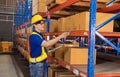 Professional Man Worker wearing hard hat checks stock and inventory with Clipboard in the retail of shelves with goods Royalty Free Stock Photo