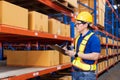 Professional Man Worker wearing hard hat checks stock and inventory with Clipboard in the retail of shelves with goods Royalty Free Stock Photo