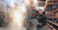 Professional Man Worker wearing hard hat checks stock and inventory with Laptop Computer in the retail of shelves with goods Royalty Free Stock Photo