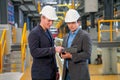 Professional manager or engineer workers discuss together with tablet in front of electrical or metro train in the factory