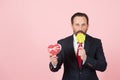Professional manager tests orange lollipop. Man loves candy and makes present with heart box and ribbon. Royalty Free Stock Photo