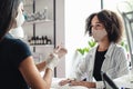 Professional manicure master and social distancing. Asian woman in protective mask put on rubber gloves to start working