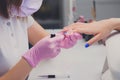 Professional manicure process in beauty salon. Closeup manicurist applies nail polish