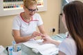 Professional manicurist removing polish from female client& x27;s nails with cotton pad at table in nail salon. Royalty Free Stock Photo