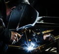 Professional mask protected welder man working on metal welding and sparks metal Royalty Free Stock Photo