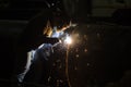 Professional mask protected welder man working on metal welding and sparks of metal at night. Employee welding steel with sparks Royalty Free Stock Photo
