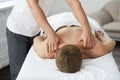 Professional massage therapist is treating a male patient in apartment.