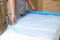 Woman massage therapist spreading disposable sheet on massage table