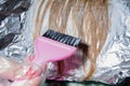 Professional master stylist applying hair color and highlights in the beauty salon. Pink brush in the hands of a hairdresser