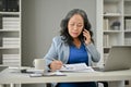 A professional mature Asian businesswoman is focusing on her work while talking on the phone Royalty Free Stock Photo